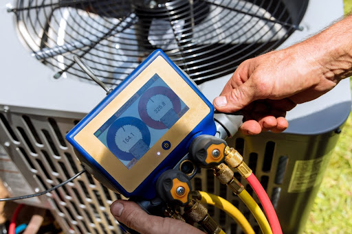 An AC technicians checking the refrigerant levels in an air conditioning system during a maintenance appointment.
